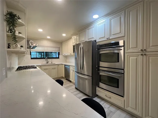 a kitchen with stainless steel appliances a stove a sink and a refrigerator
