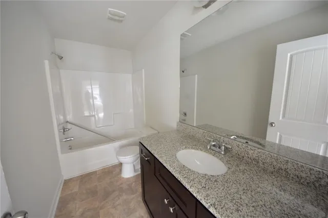 a bathroom with a granite countertop sink a toilet and tub