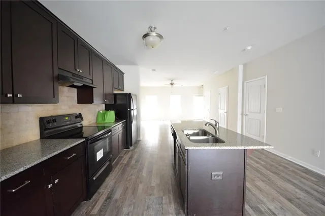 a kitchen with granite countertop kitchen island stainless steel appliances a sink stove and refrigerator