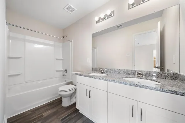 a bathroom with a granite countertop sink toilet mirror and bathtub