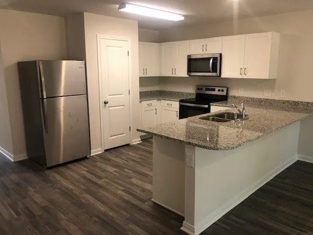 a kitchen with granite countertop a refrigerator and a stove top oven