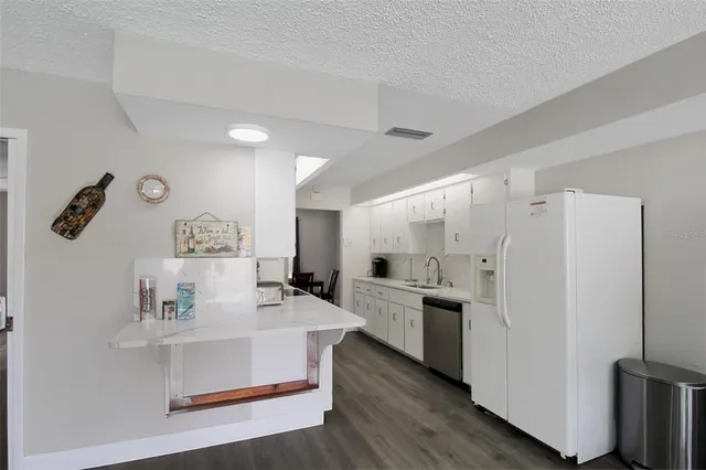 a kitchen with white cabinets and refrigerator