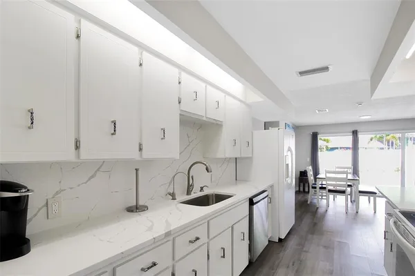 a kitchen with granite countertop a sink a stove refrigerator and cabinets