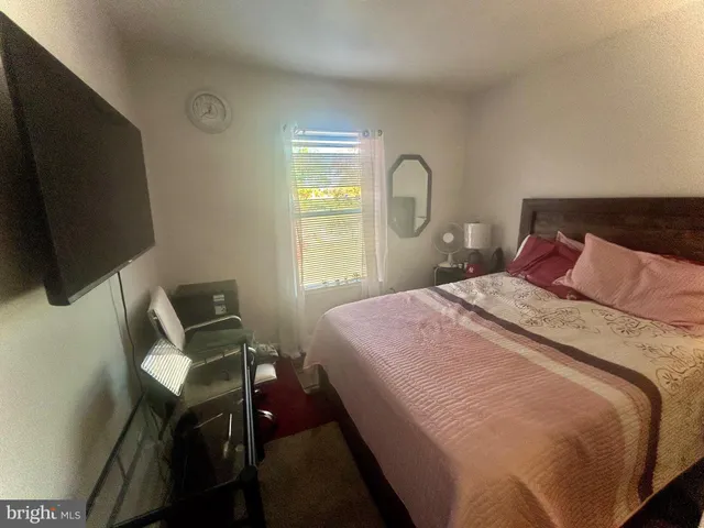 a bedroom with a bed tv and a window