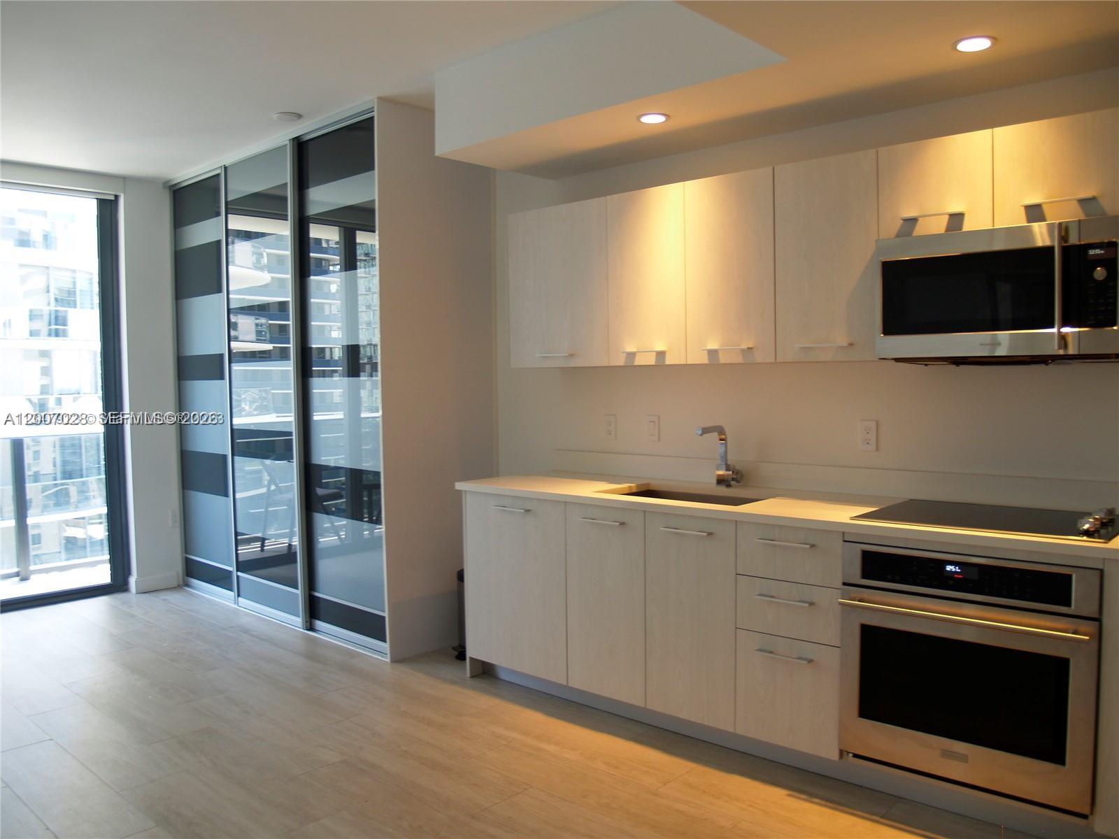 55 Southwest 9th Street, Unit 2502 Miami, FL 33130 - Photo 7 of 27 a kitchen with stainless steel appliances granite countertop a sink and a stove top oven