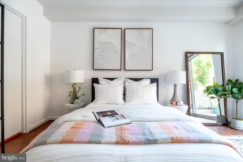 a bedroom with a bed a mirror and a potted plant