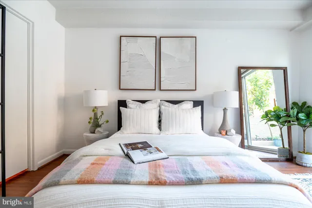 a bedroom with a bed a mirror and a potted plant