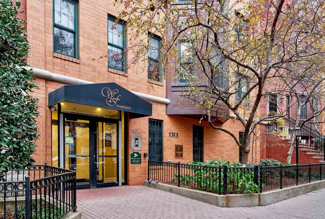 front view of a brick house with a large trees