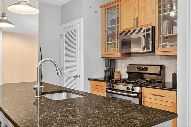 a kitchen with stainless steel appliances granite countertop a sink a stove and a microwave