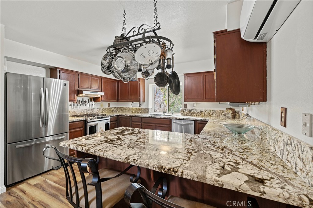 921 Piru Way Frazier Park, CA 93225 - Photo 15 of 62 a kitchen with kitchen island granite countertop a table chairs stove and refrigerator