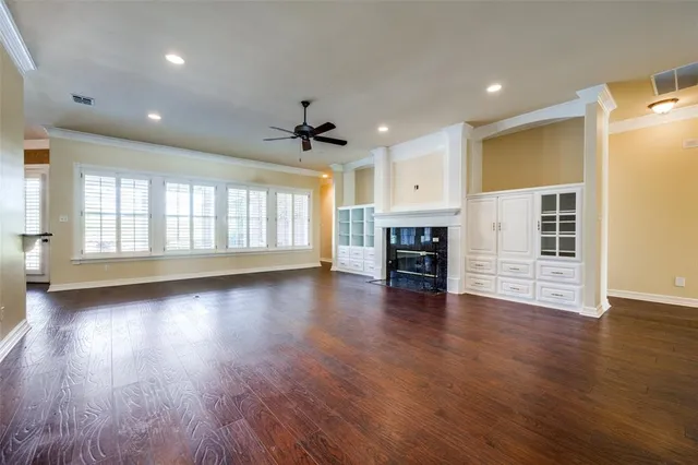 an empty room with wooden floor and a kitchen