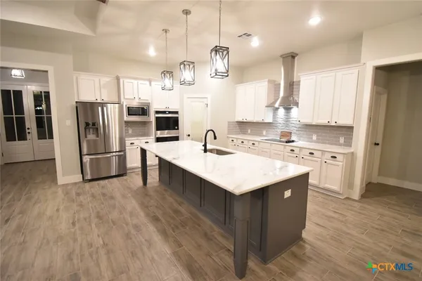 a kitchen with stainless steel appliances kitchen island a sink and a refrigerator