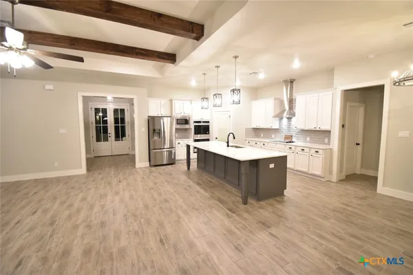 a large kitchen with a large counter top a sink stainless steel appliances and cabinets