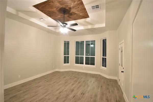 a view of an empty room with wooden floor and a window