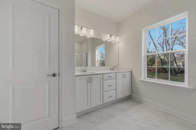 a spacious bathroom with a double vanity sink a mirror and a shower