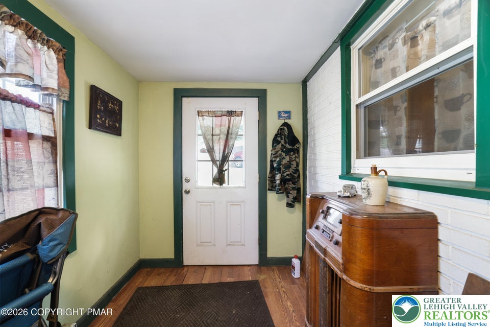 Rich wood flooring runs throughout this welcoming entryway featuring a classic brick accent wall.