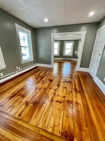 a view of empty room with window and wooden floor