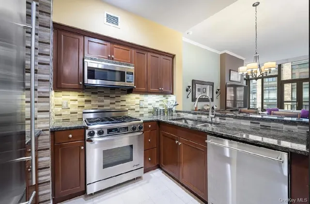 a kitchen with stainless steel appliances granite countertop wooden cabinets stove top oven and sink