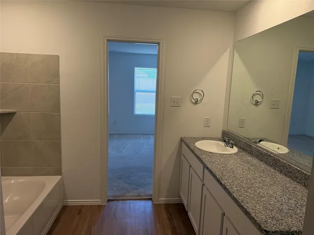 a bathroom with a granite countertop tub sink and mirror