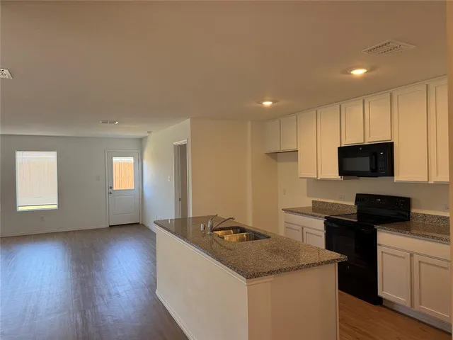 a kitchen with granite countertop a sink a refrigerator and window