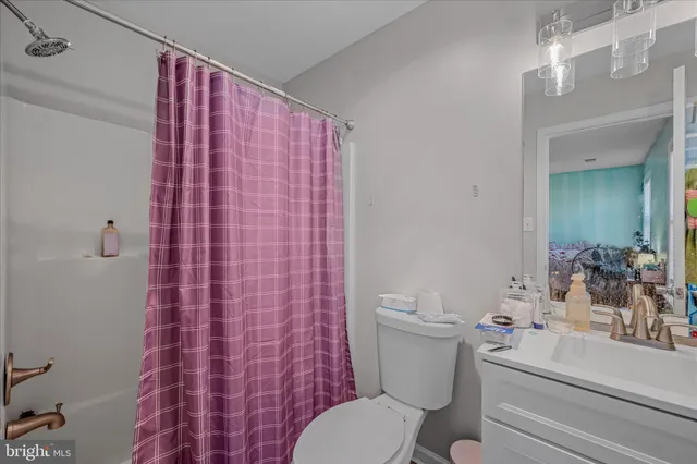 a bathroom with a sink a toilet a mirror and shower curtain