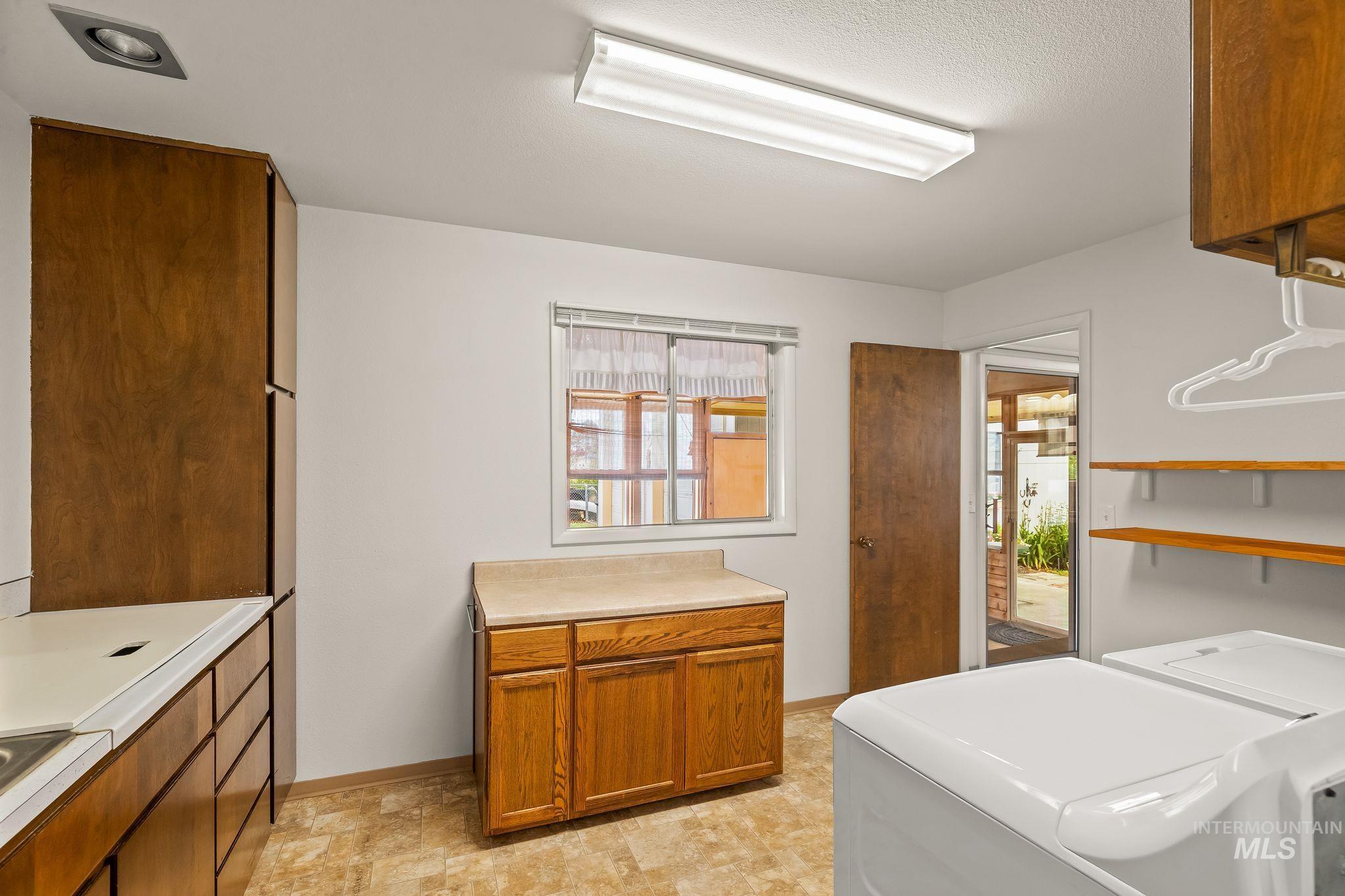 1721 3rd Street Lewiston, ID 83501 - Photo 36 of 45 Functional utility room featuring wood-finish cabinetry, a window with natural light, and durable vinyl flooring