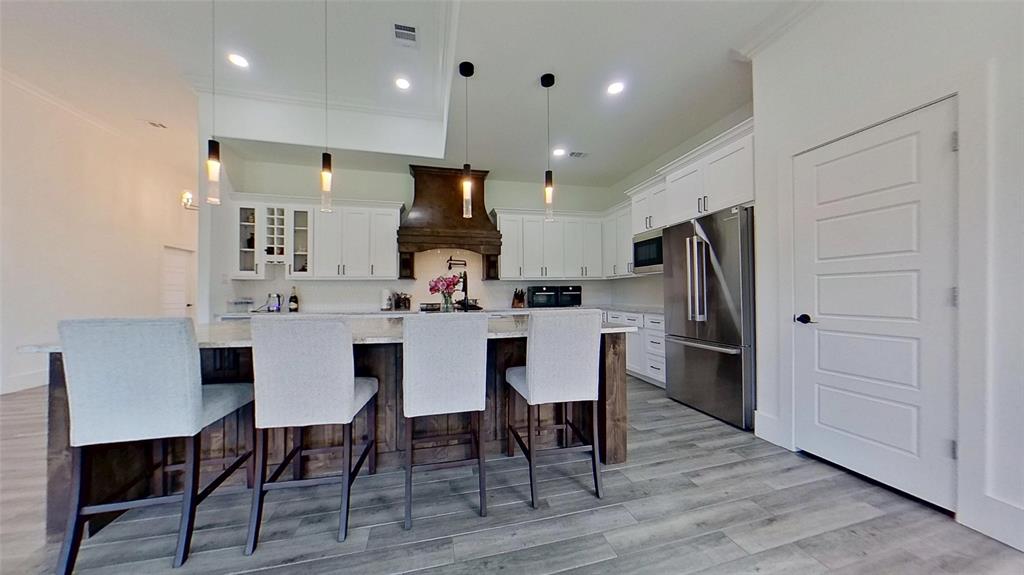 3248 North Cardinal Road Azle, TX 76020 - Photo 10 of 29 Spacious kitchen featuring an expansive center island, white cabinetry, stainless steel appliances, a decorative wood range hood, and tile flooring