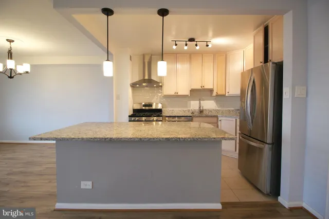 a kitchen with kitchen island a counter top a refrigerator and cabinets