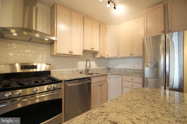 a kitchen with stainless steel appliances granite countertop a stove a sink and a refrigerator