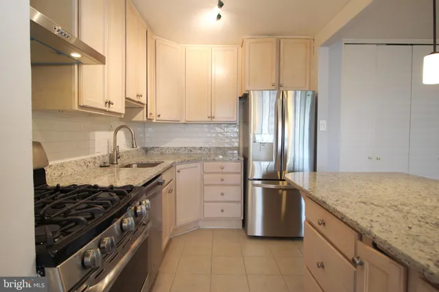 a kitchen with stainless steel appliances granite countertop a sink stove and refrigerator