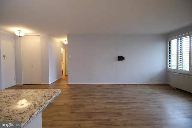 a view of an empty room with window and wooden floor