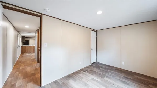 a view of a hallway with wooden floor and a bathroom