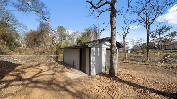 a backyard of a house with large trees and wooden fence