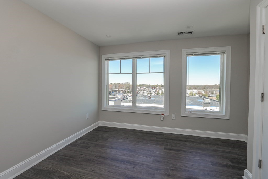 918 Providence Highway, Unit 314 Dedham, MA 02026 - Photo 6 of 10 an empty room with wooden floor and windows