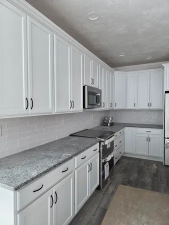 a kitchen with granite countertop white cabinets and stainless steel appliances
