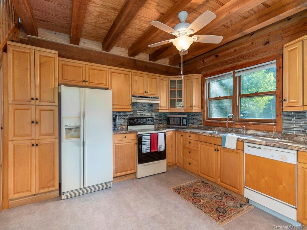 119 Loop Road Clyde, NC 28721 - Photo 6 of 18 a kitchen with stainless steel appliances granite countertop a stove a refrigerator a sink a dining table and chairs with wooden floor