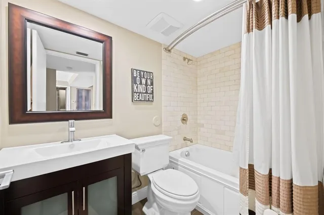 a bathroom with a toilet a sink a mirror a vanity and shower