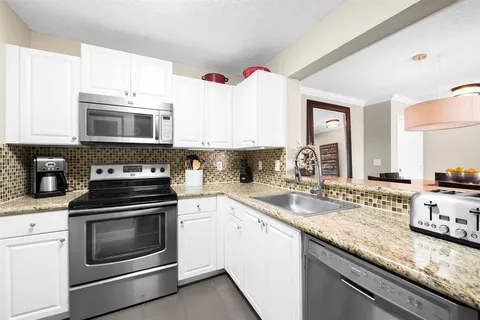 a kitchen with granite countertop a stove sink and cabinets