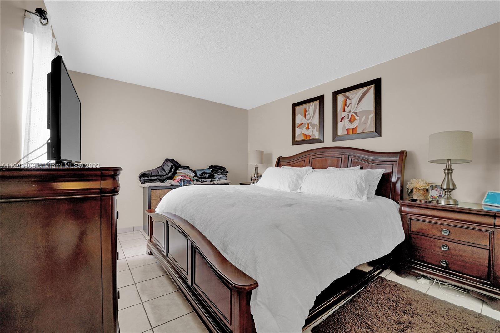 9331 Southwest 4th Street, Unit 118B Miami, FL 33174 - Photo 12 of 16 a bedroom with a bed and a tv on the dresser