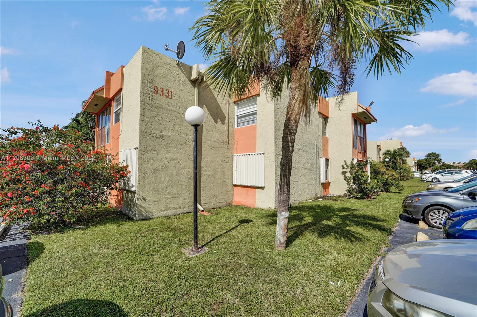 9331 Southwest 4th Street, Unit 118B Miami, FL 33174 - Photo 16 of 16 a front view of a house with a yard and palm trees