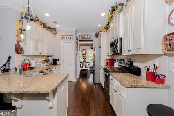 a kitchen with granite countertop a white stove top oven and white cabinets