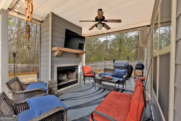 a living room with furniture a ceiling fan a fireplace and a large window
