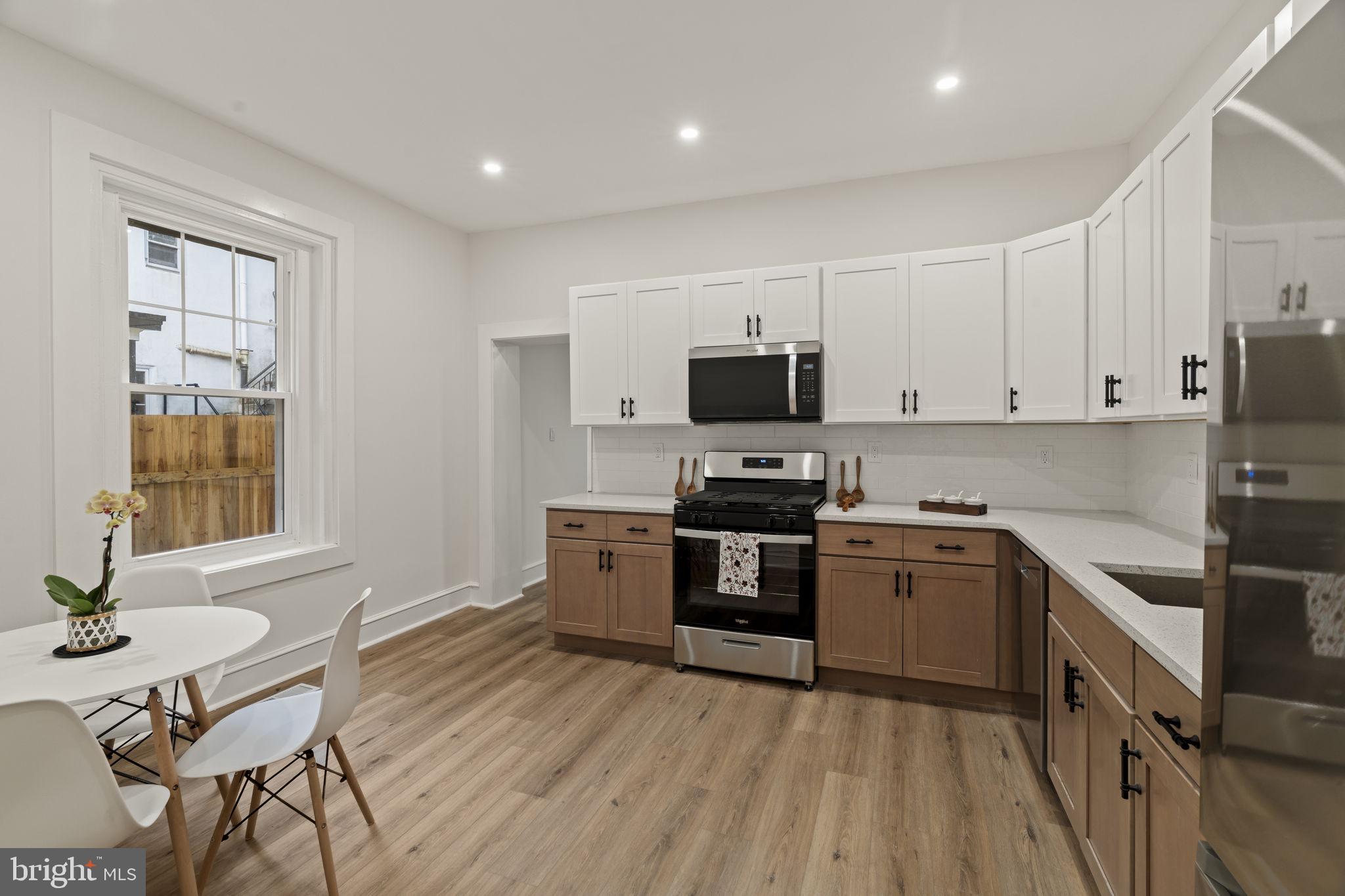 147 Harvey Street Philadelphia, PA 19144 - Photo 3 of 37 a kitchen with stainless steel appliances a stove a sink dishwasher a microwave oven with a dining table and chairs