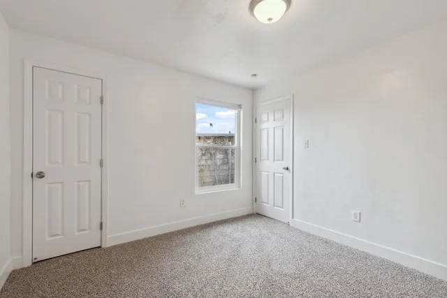 a view of an empty room with window and closet area