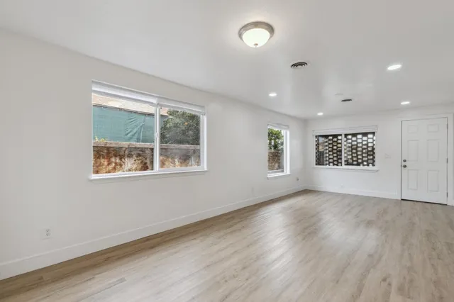 an empty room with wooden floor and windows