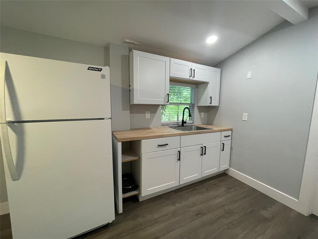2113 River Road, Unit A San Marcos, TX 78666 - Photo 11 of 12 Kitchen with freestanding refrigerator, white cabinetry, dark wood finished floors, butcher block countertops, and lofted ceiling