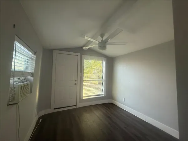 an empty room with wooden floor cabinet and windows