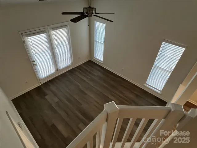 a view of an empty room with wooden floor and staircase