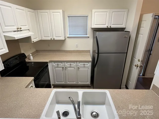 a kitchen with a sink a refrigerator and cabinets