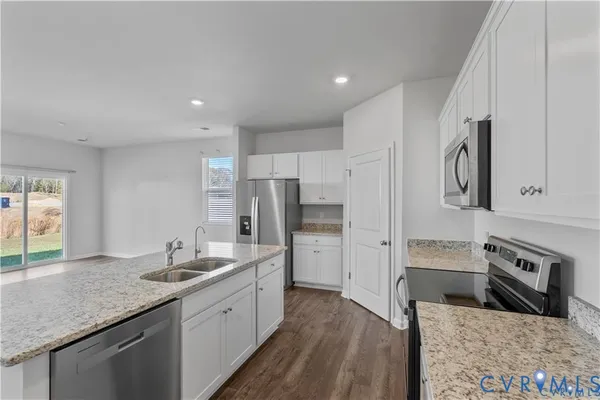 a white kitchen with stainless steel appliances granite countertop a refrigerator a stove and a sink